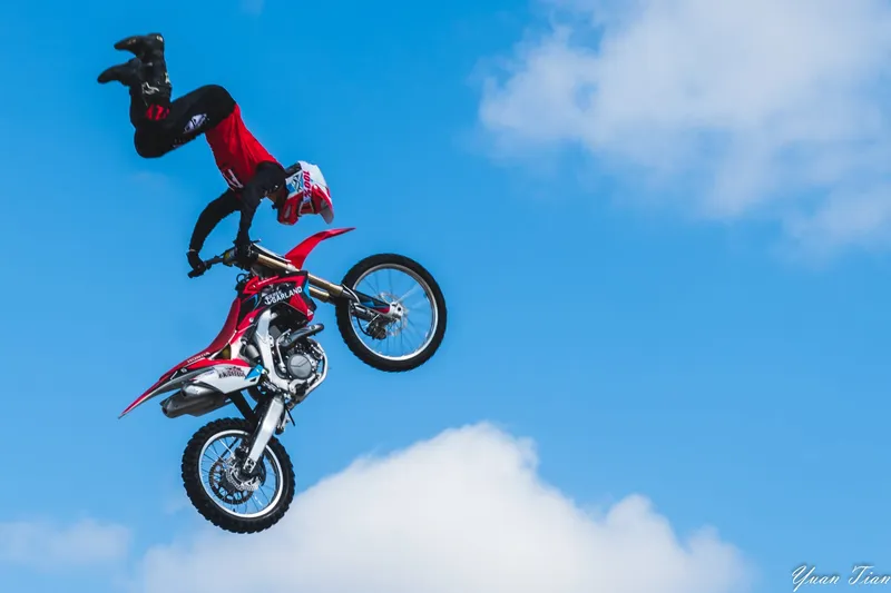 Freestyle motocross rider performing an inverted trick high above the clouds
